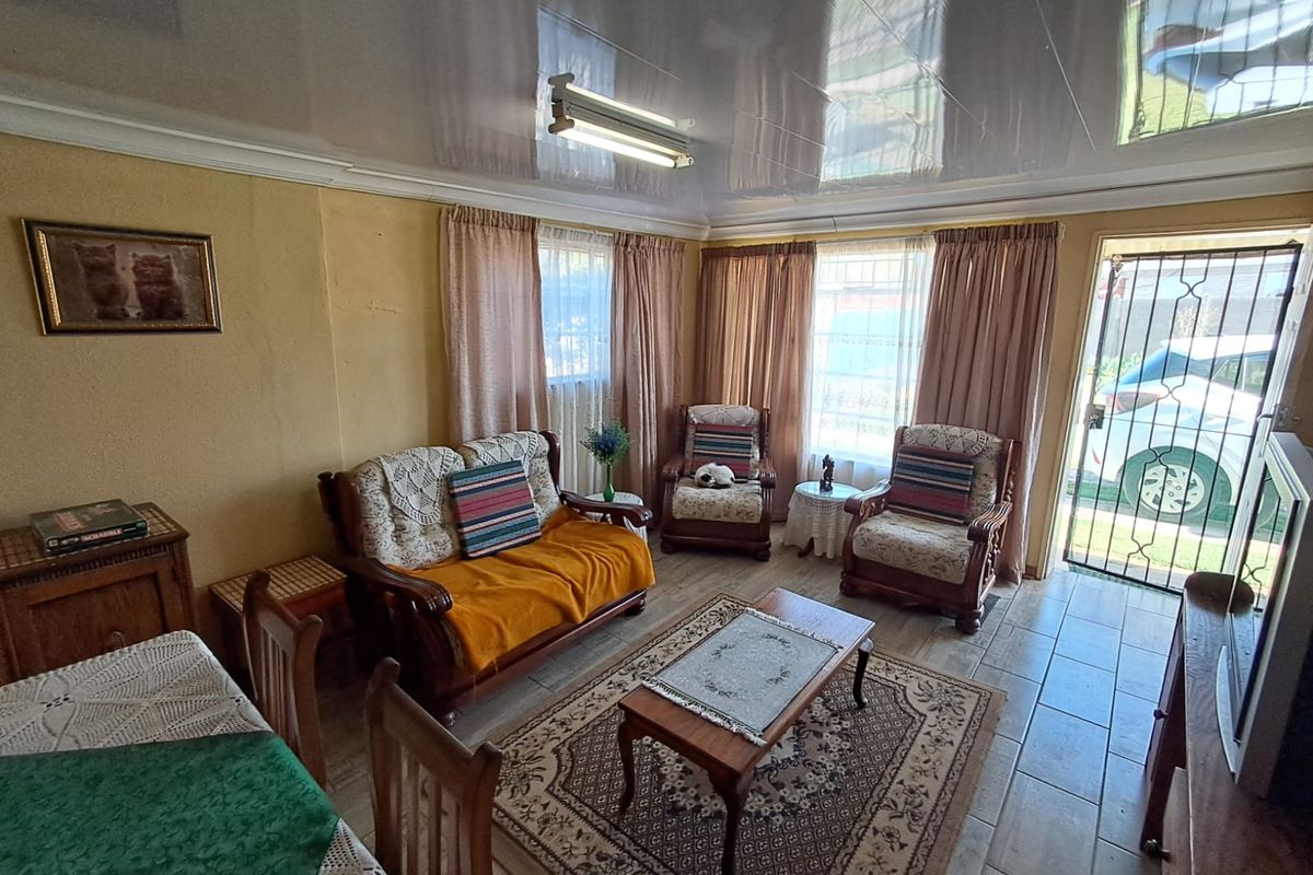 A living room featuring tiled flooring, a glossy ceiling finish, and direct access to the exterior via a security gate.