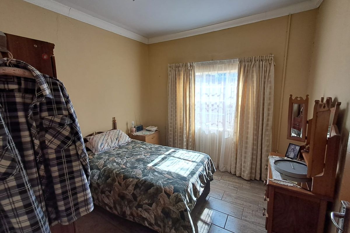A bedroom featuring tiled flooring and neutral wall finishes, offering a functional space with potential for modernization and aesthetic updates.