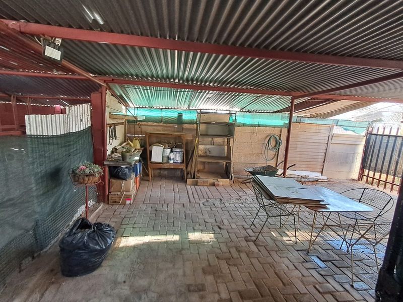A covered outdoor patio area featuring brick paving and a corrugated iron roof structure, suitable for renovation or outdoor entertainment space development.