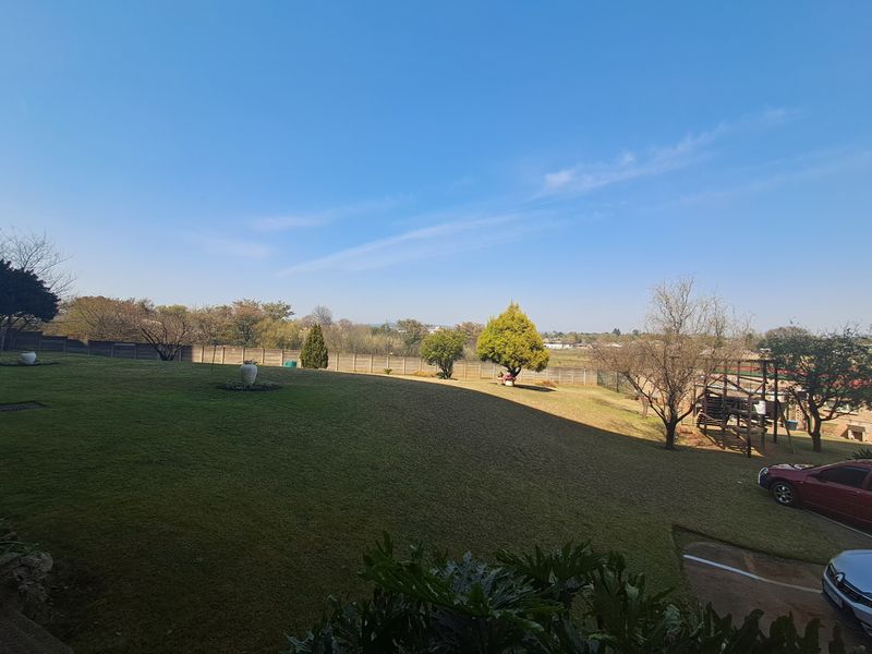 A spacious, well-maintained garden area featuring a large lawn and secure perimeter boundary wall, offering an open outdoor space.