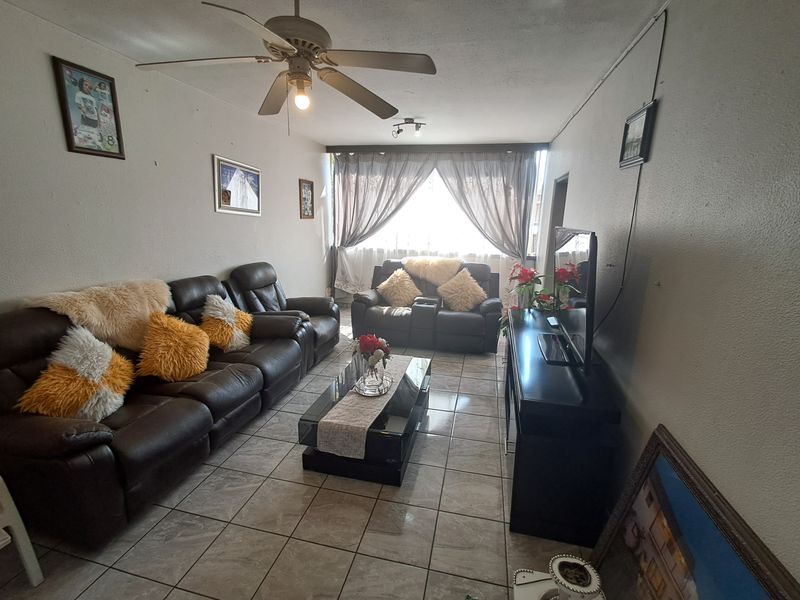 A living room featuring ceramic tile flooring and a ceiling fan, offering a functional space with potential for cosmetic updates.