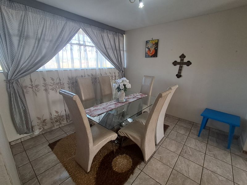 A functional dining area featuring tiled flooring and a large window with curtains, providing a bright space for meals.
