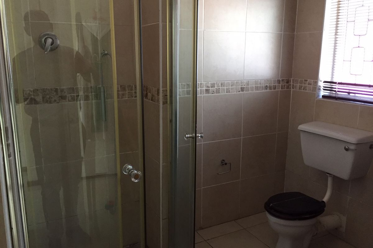 A functional bathroom featuring a shower enclosure, ceramic tiling, and a standard toilet suite.