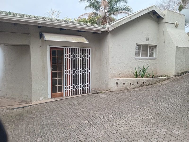 Front exterior view of the property featuring a cobblestone driveway, security gate, and a textured facade with a tiled roof.