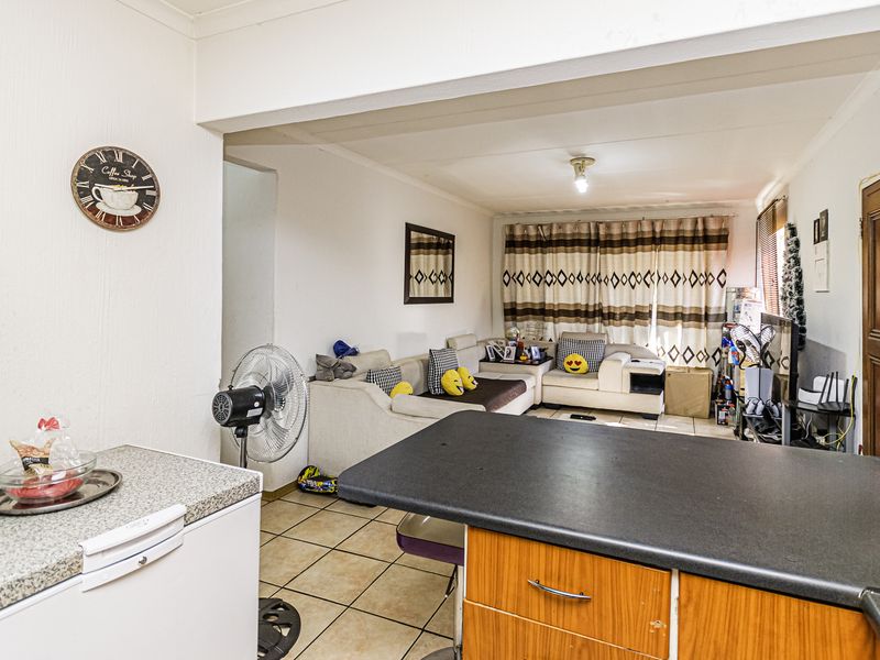 Open-plan living area featuring tiled flooring and a kitchen island with laminate cabinetry, connecting the kitchen space to the main living room.