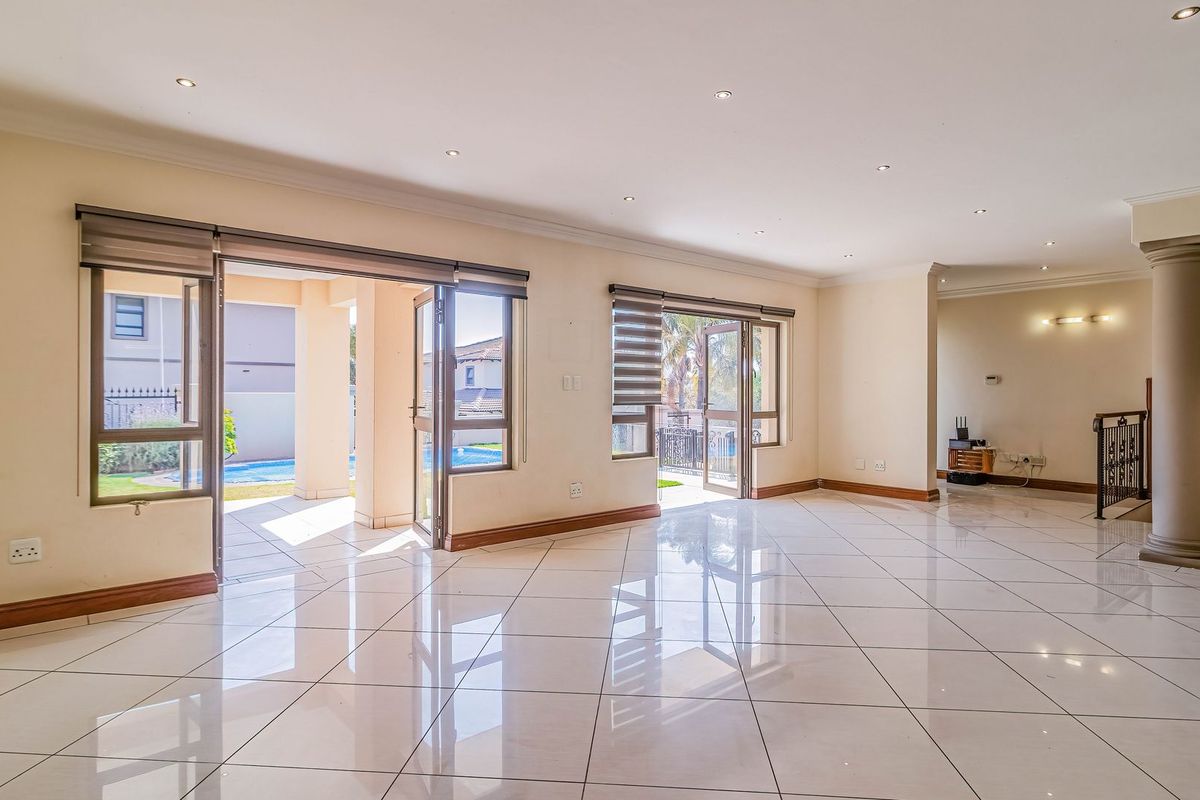Spacious, light-filled living area featuring polished porcelain floor tiles, recessed lighting, and multiple sliding glass doors providing seamless access to the outdoor patio area.