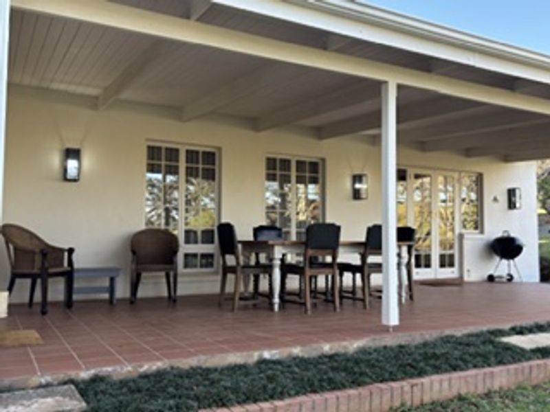 A spacious covered patio featuring tiled flooring, wall-mounted lighting, and direct access to the interior through classic french doors.
