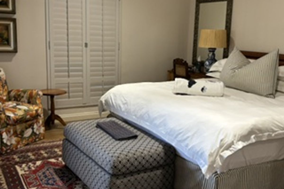 A well-maintained bedroom featuring classic plantation shutters and neutral wall finishes, providing a comfortable and private living space.