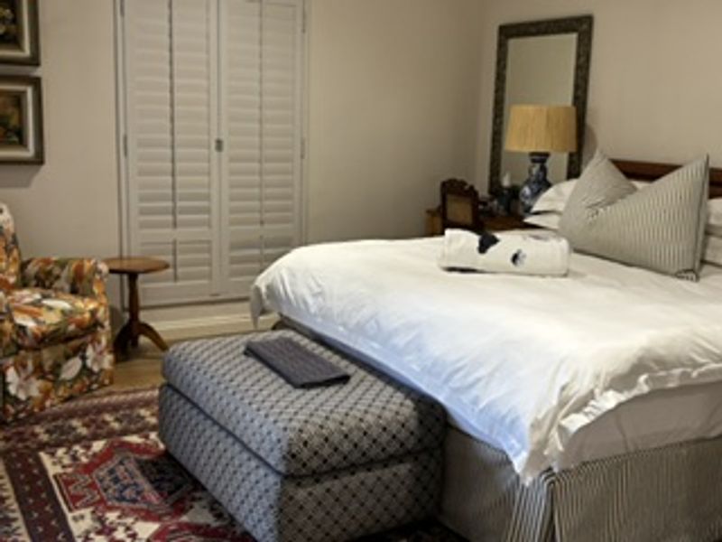 A well-maintained bedroom featuring classic plantation shutters and neutral wall finishes, providing a comfortable and private living space.