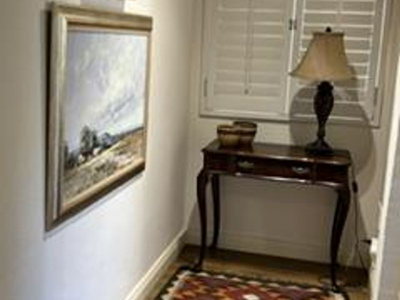A well-maintained hallway featuring plantation shutters, decorative coving, and classic skirting boards.