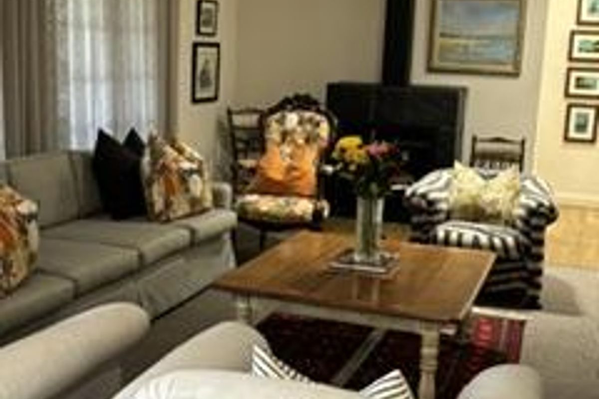 A cozy living room featuring a prominent black freestanding fireplace, crown molding, and large windows with elegant drapery.