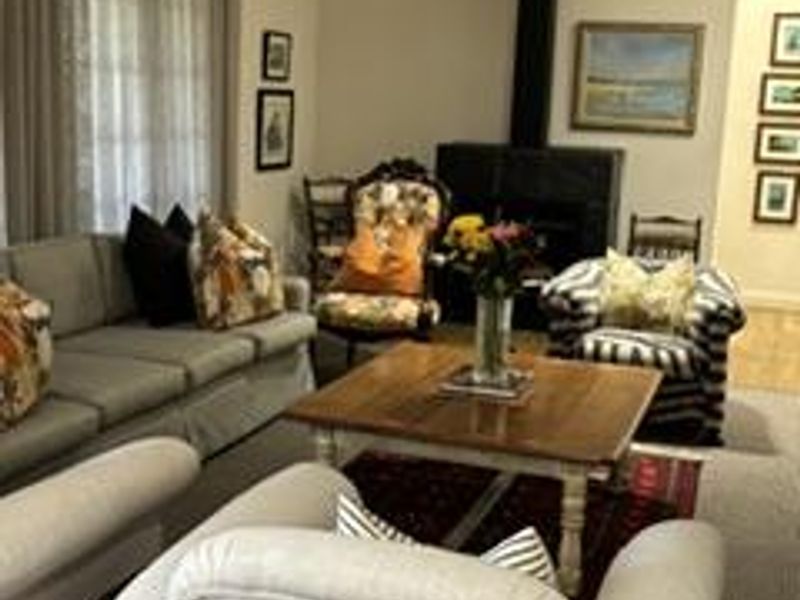 A cozy living room featuring a prominent black freestanding fireplace, crown molding, and large windows with elegant drapery.