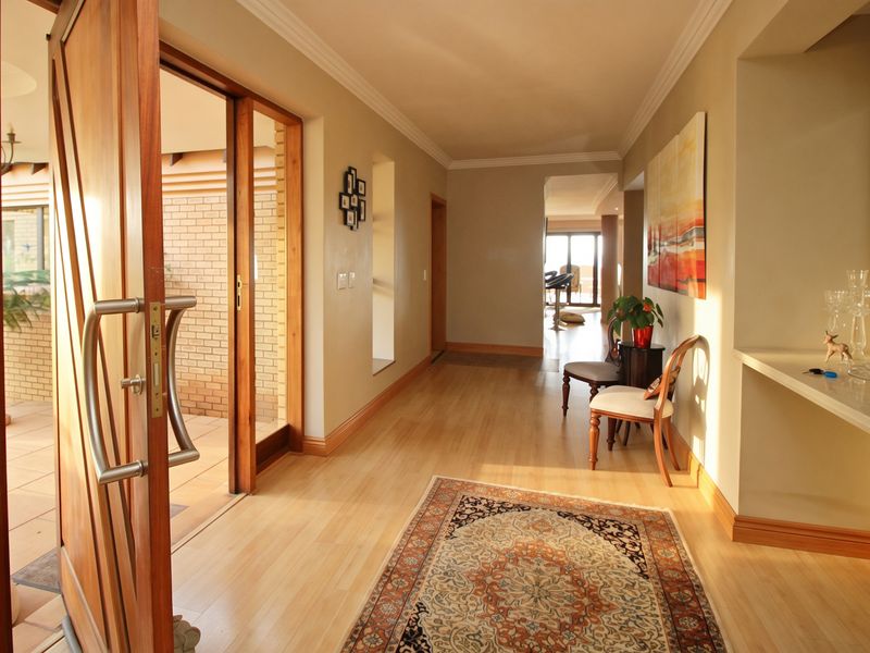 Welcoming entrance hall featuring warm wooden flooring, crown molding, and a built-in wall niche, leading through to the main living areas.
