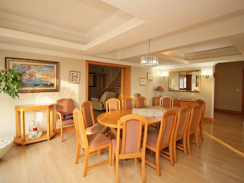 Spacious dining room featuring a recessed tray ceiling, crown molding, and light-toned laminate flooring, providing an open and inviting atmosphere for formal gatherings.