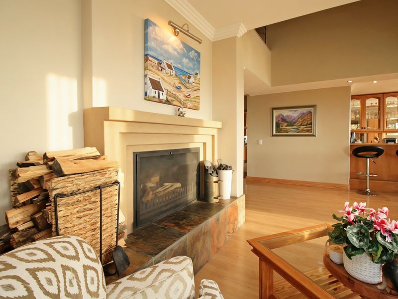 A cozy living room featuring a fireplace with a slate hearth, laminate flooring, and an adjacent built-in bar area.