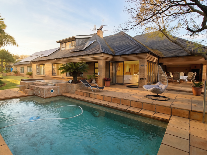 Spacious rear patio area featuring a swimming pool, stone-clad surround, and seamless indoor-outdoor flow through large sliding glass doors to the main living space.