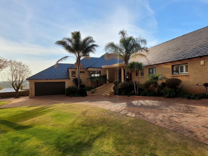 A well-maintained brick family home featuring a spacious paved driveway, double garage, and established garden with mature palm trees.