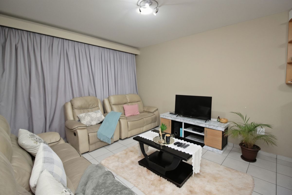A comfortable living room featuring tiled flooring and neutral wall tones, providing a functional space for relaxation.