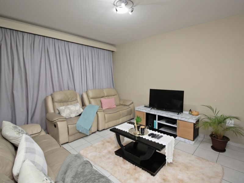 A comfortable living room featuring tiled flooring and neutral wall tones, providing a functional space for relaxation.