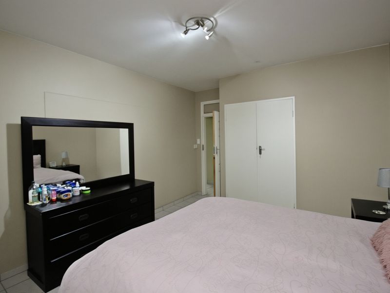 A bedroom featuring neutral wall tones, tiled flooring, and a built-in wardrobe, providing a functional and clean living space.