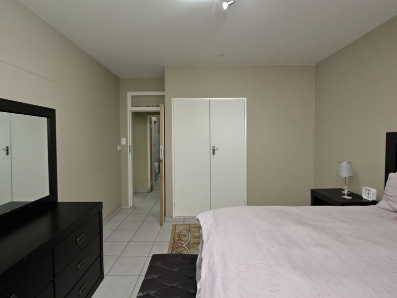 A bedroom featuring neutral wall tones, tiled flooring, and built-in cupboard storage with direct access to an adjoining room.