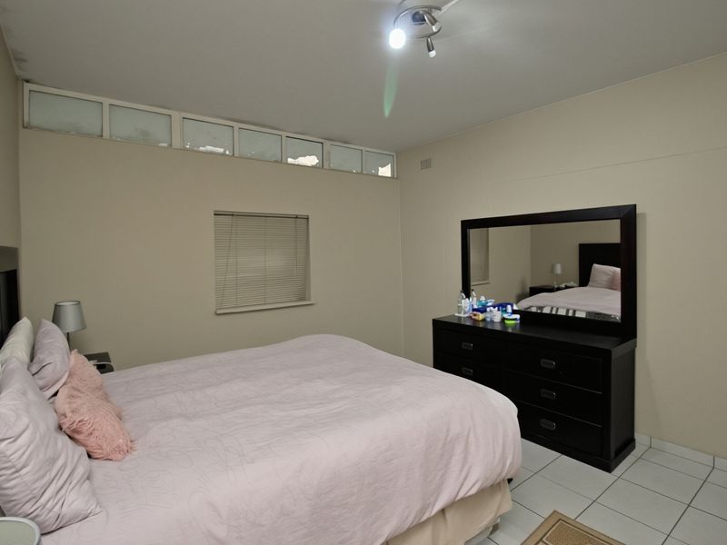 A bedroom featuring tiled flooring, clerestory windows for natural light, and venetian blinds.