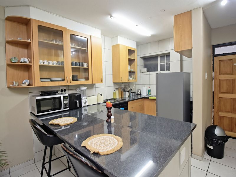 A functional kitchen featuring laminate cabinetry, granite countertops with a breakfast bar, and tiled flooring, offering a practical layout for daily use.