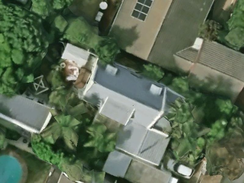 An aerial view of the property showing the roof layout and surrounding garden area with a swimming pool.