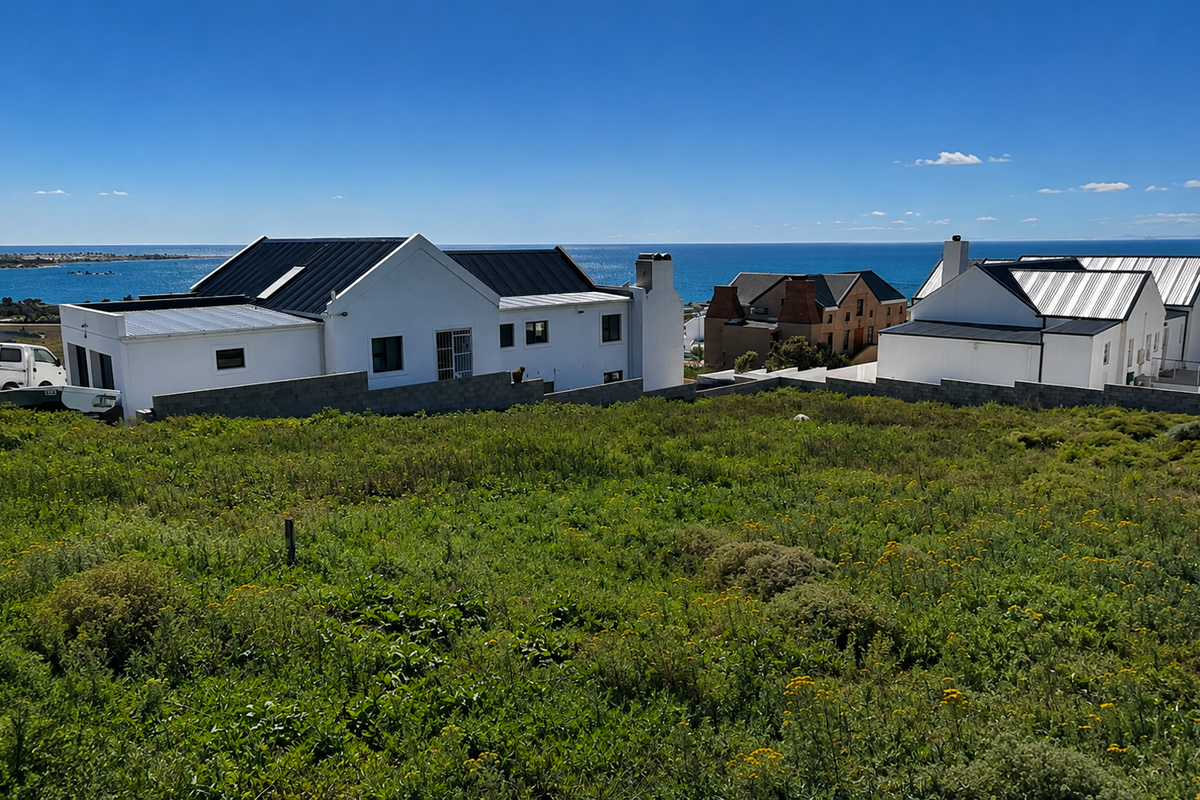 A scenic view overlooking a vacant residential plot with established coastal homes and a clear ocean horizon in the background.