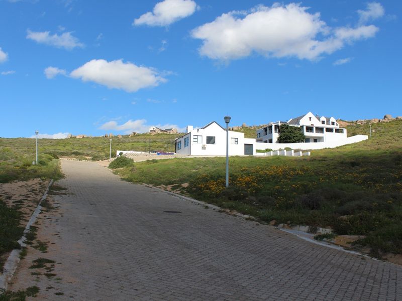A view of the paved access road leading up to the residential property, featuring surrounding natural landscape and clear blue skies.
