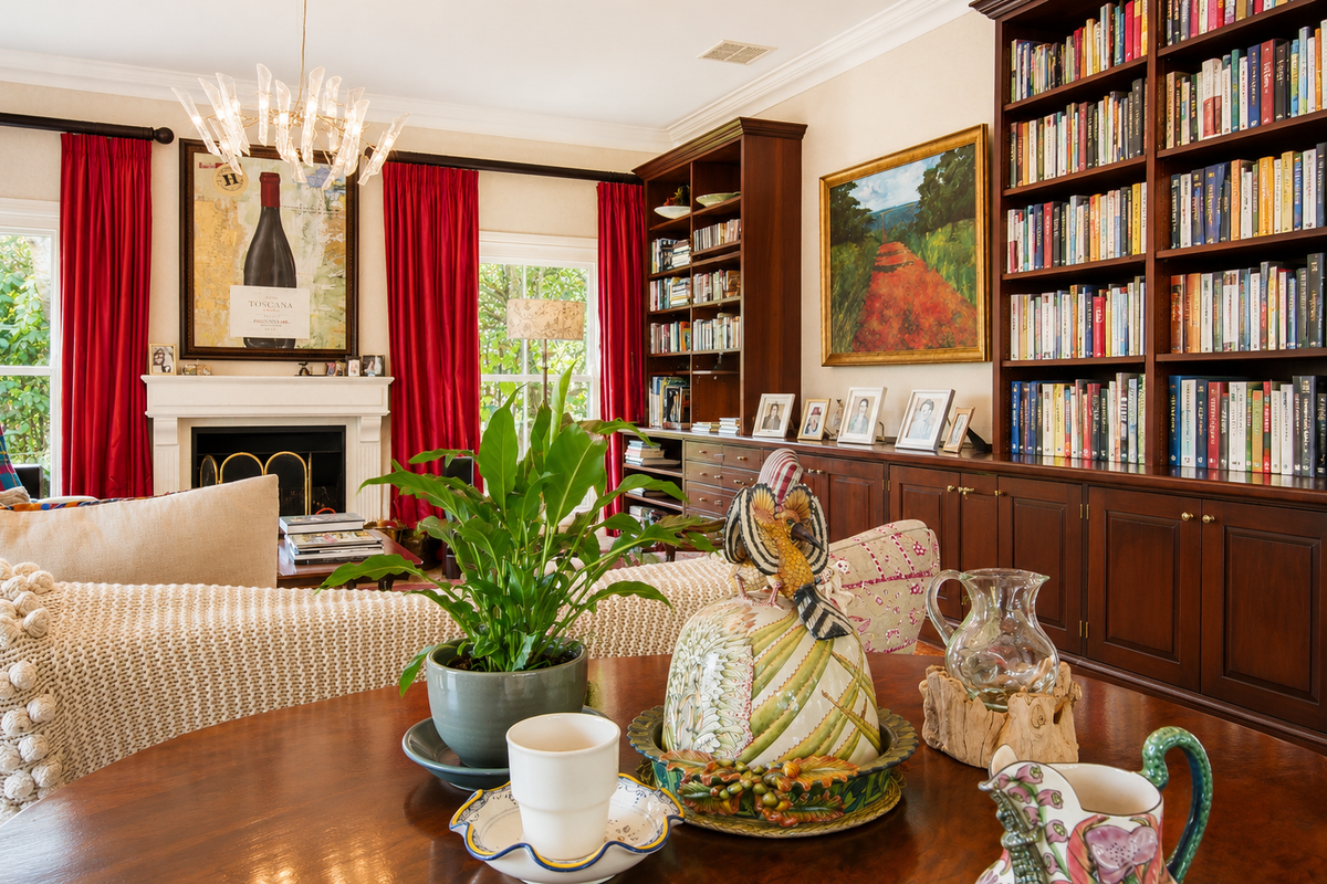 A well-appointed living room featuring extensive built-in wooden cabinetry, bookshelves, and a classic fireplace with a decorative mantelpiece.