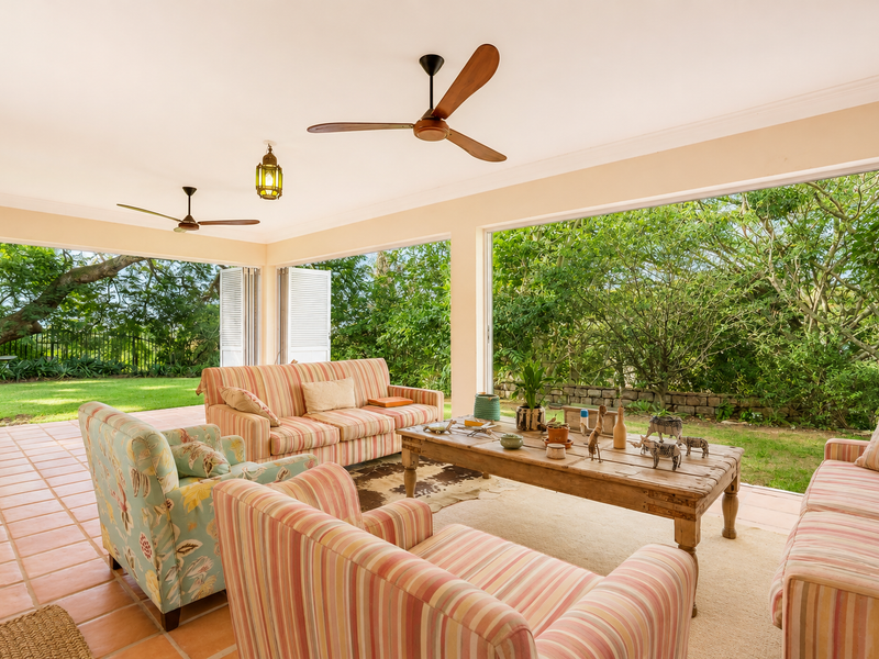 Spacious covered patio featuring terracotta flooring and large bi-fold doors that open onto a lush garden, providing a seamless indoor-outdoor living experience.