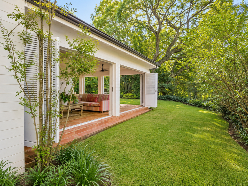 A covered patio featuring terracotta tiling and bi-fold doors that open onto a lush, well-maintained garden area.