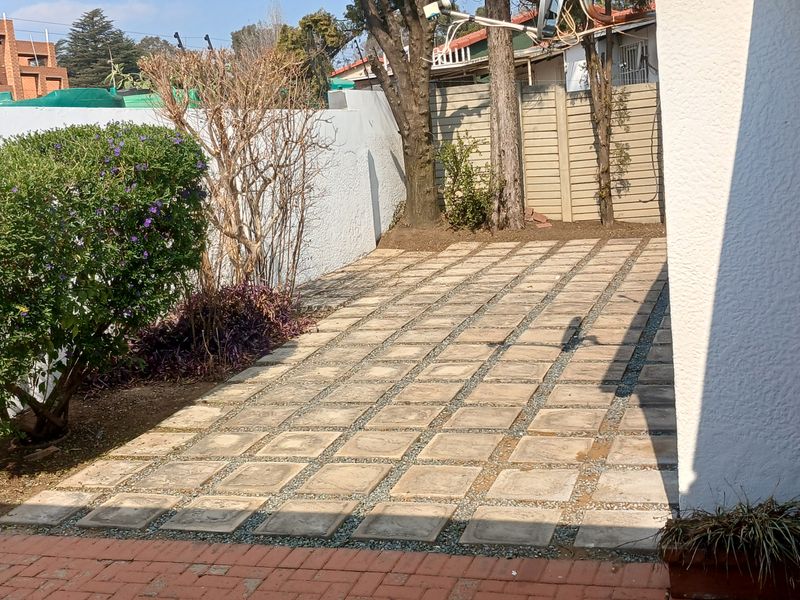 A private rear courtyard featuring a paved patio area, enclosed by boundary walls and established garden greenery.
