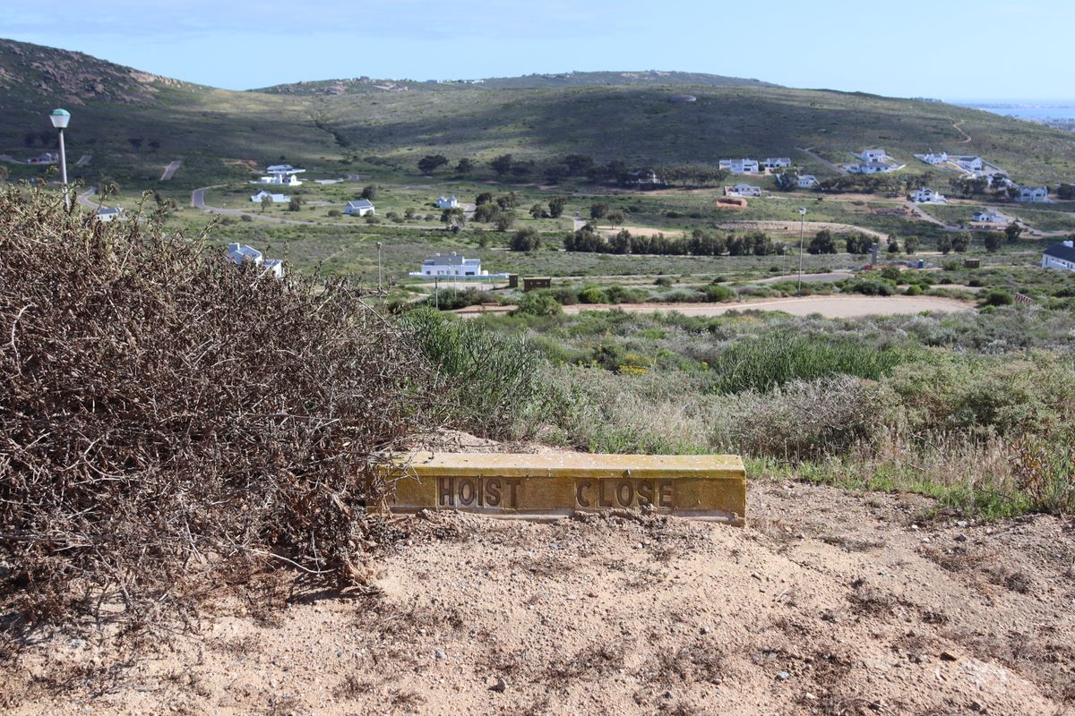 A scenic view overlooking a residential estate with rolling hills and distant coastal landscape.
