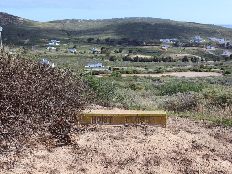 A scenic view overlooking a residential estate with rolling hills and distant coastal landscape.