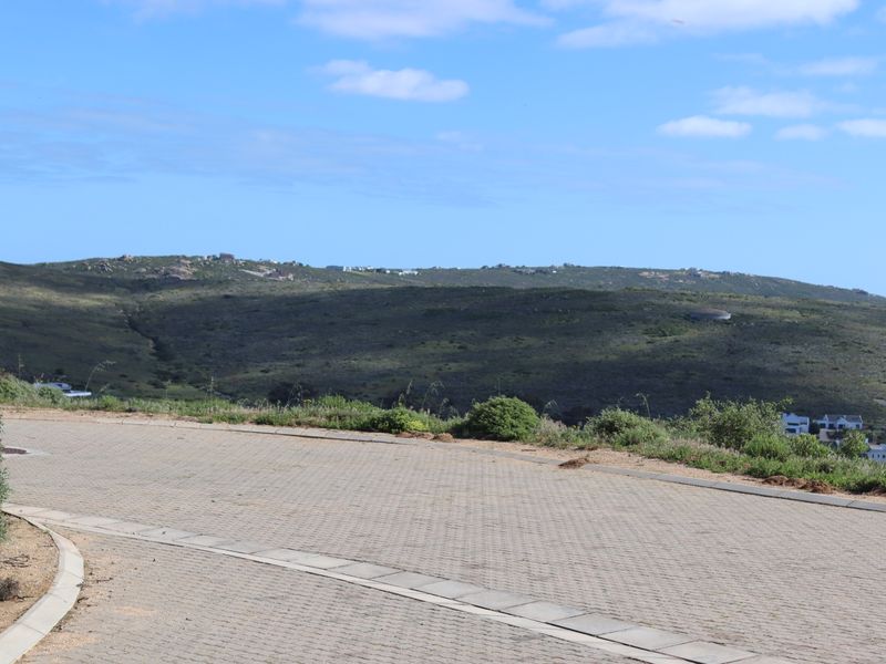 A view of the surrounding landscape and hills from a paved residential street.