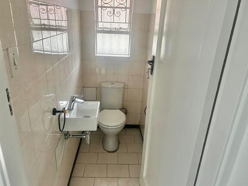 A compact guest bathroom featuring a wall-mounted basin, toilet, and neutral ceramic tiling throughout.