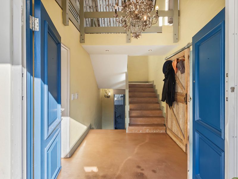 Spacious entrance hall featuring a staircase, exposed timber ceiling beams, and a rustic sliding barn door, providing a unique architectural welcome to the home.