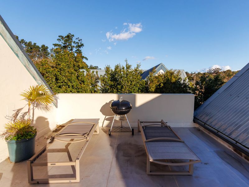 An open-air rooftop balcony featuring a parapet wall and metal roofing, offering a private outdoor space with potential for enhancement.