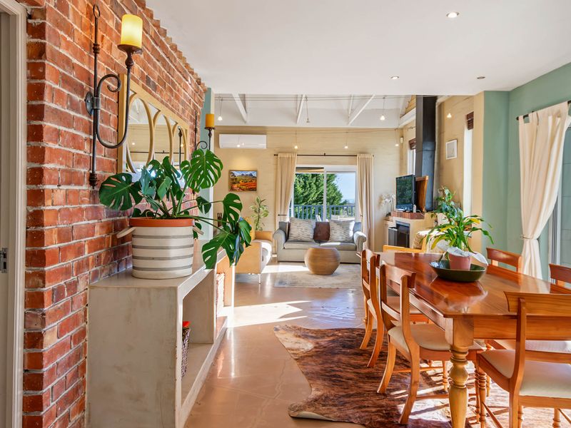 Spacious open-plan living and dining area featuring an exposed brick feature wall, fireplace, and large sliding doors leading to an outdoor space.