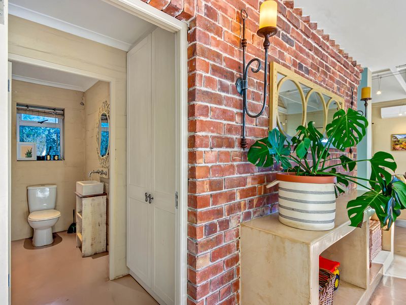 A bathroom featuring an exposed brick wall, built-in vanity with basin, and integrated storage cupboard, showcasing a rustic and character-filled design.