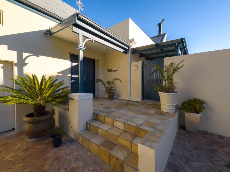 A well-maintained front entrance featuring tiled steps, a covered porch area, and brick paving, providing a welcoming approach to the home.
