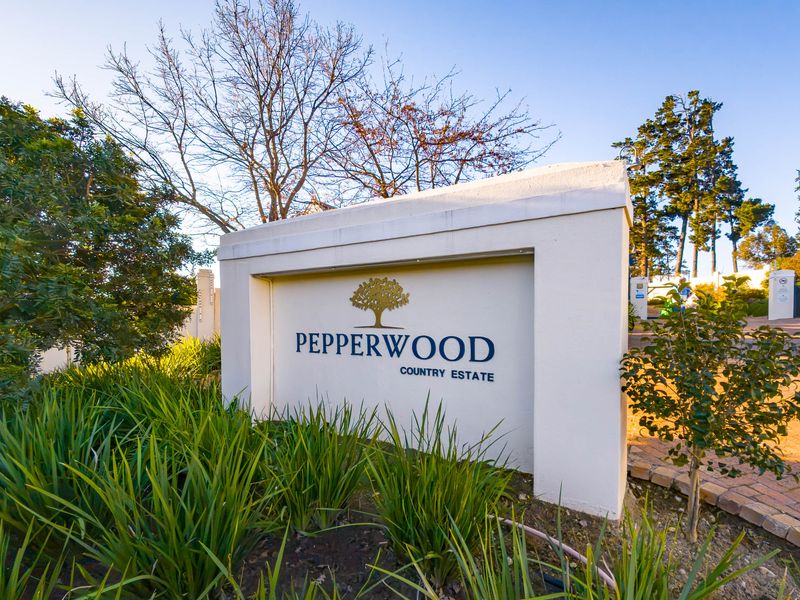 The entrance signage wall for Pepperwood Country Estate, featuring a paved driveway and established garden landscaping.