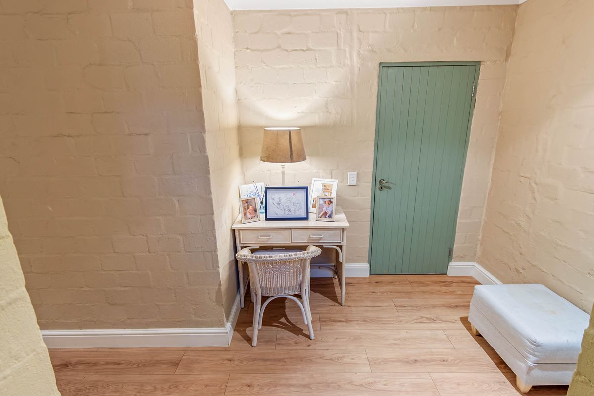 A bedroom space featuring painted brick walls, timber-look laminate flooring, and a green internal door.
