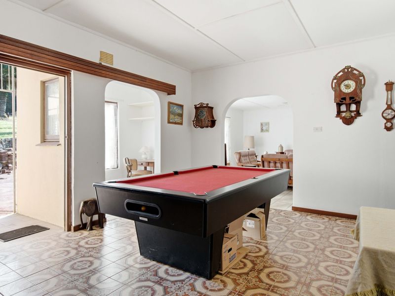 A living area featuring traditional patterned floor tiles, arched doorways leading to adjacent rooms, and direct access to an outdoor patio area.