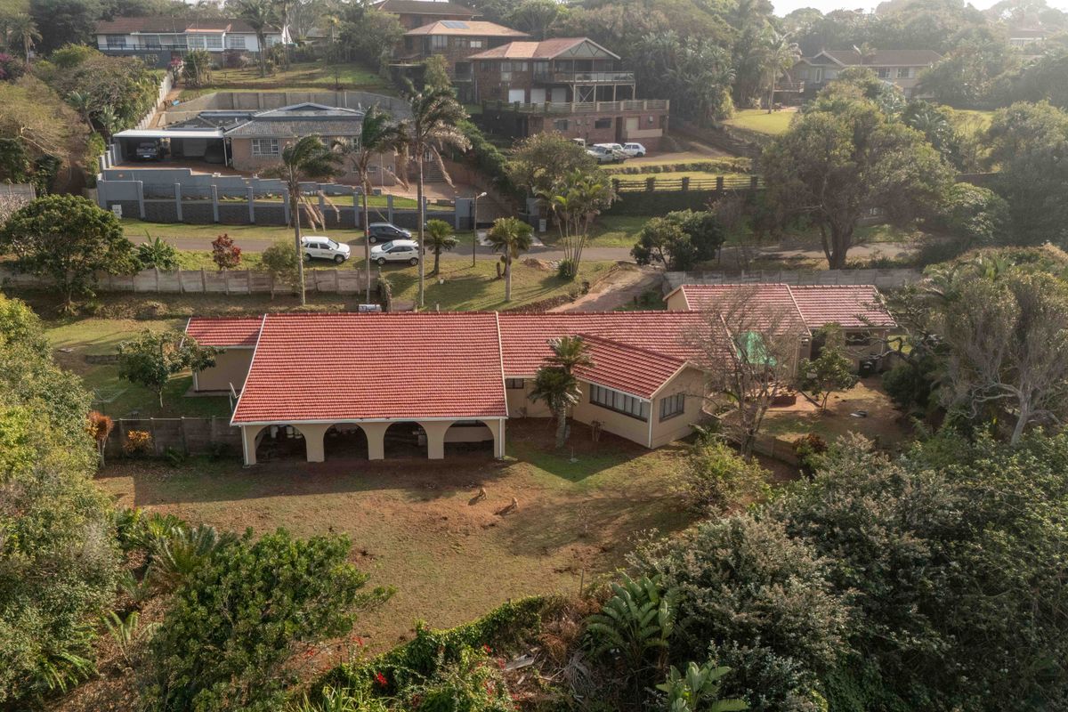 Aerial view of a single-story residential property featuring a terracotta tiled roof, a spacious covered patio with arched columns, and an expansive garden.