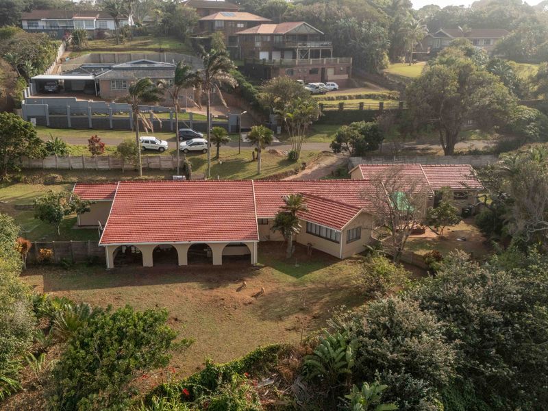 Aerial view of a single-story residential property featuring a terracotta tiled roof, a spacious covered patio with arched columns, and an expansive garden.