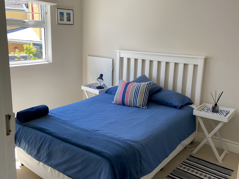 A well-maintained bedroom featuring neutral wall tones, carpeted flooring, and a window providing natural light.