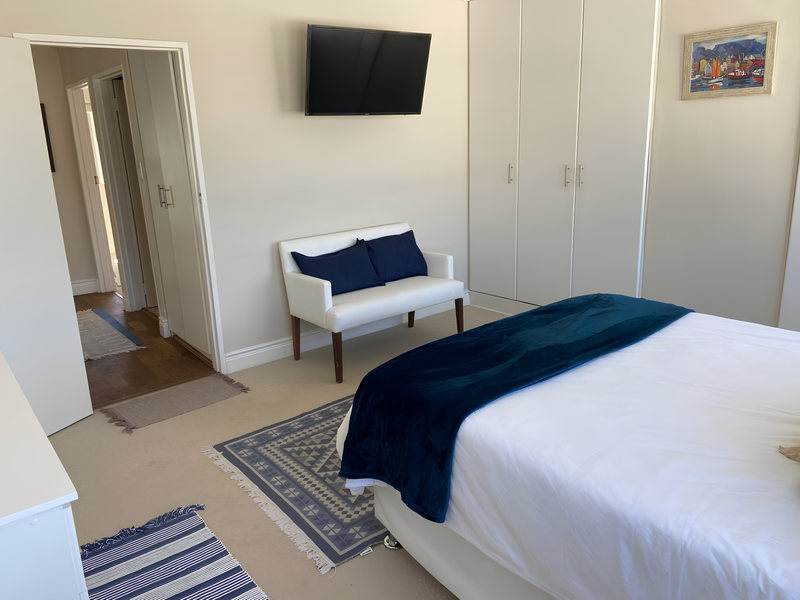 A well-maintained bedroom featuring neutral walls, carpeted flooring, and ample built-in cupboard storage with direct access to an adjoining hallway.